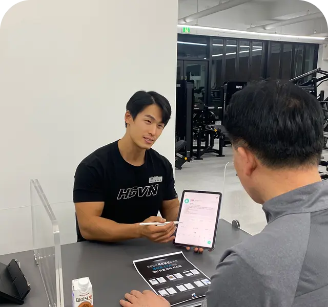 코치가 태블릿을 보여주며 회원과 상담하는 모습